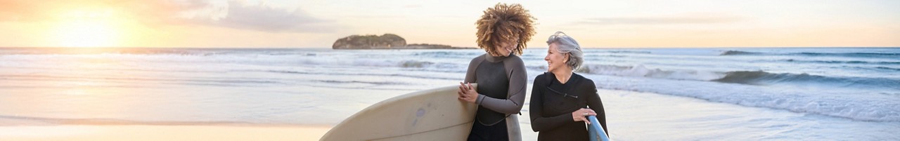 Deux femmes portent des planches de surf sur une plage