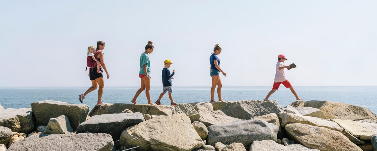 A family of 6 walking along a pile of rocks on the coast near the ocean
