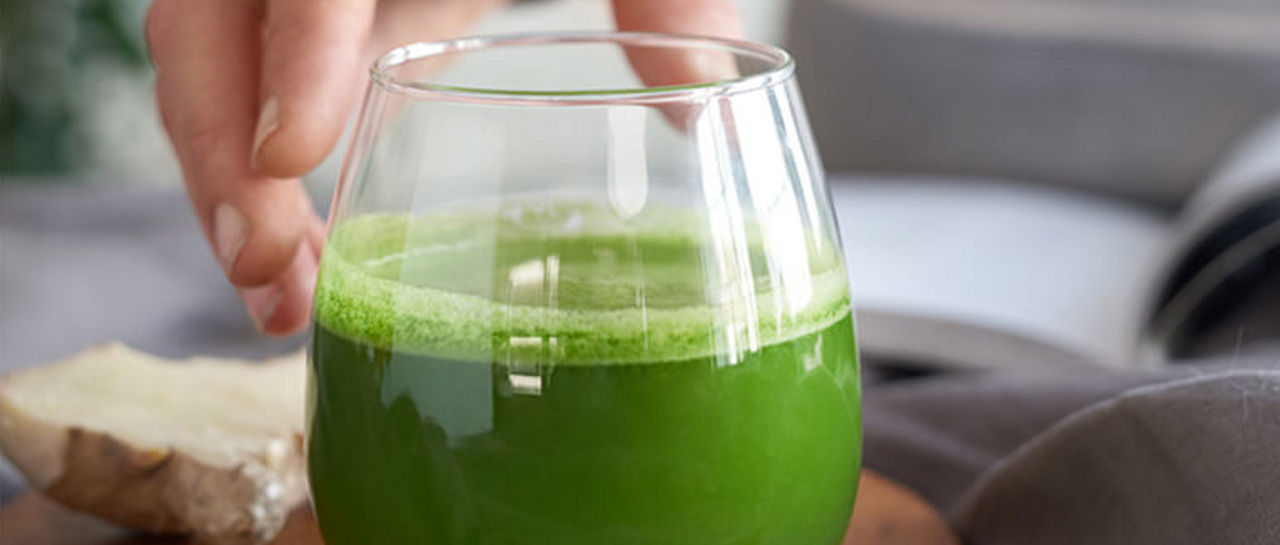 Man reaching for an organic green smoothie on a kitchen counter