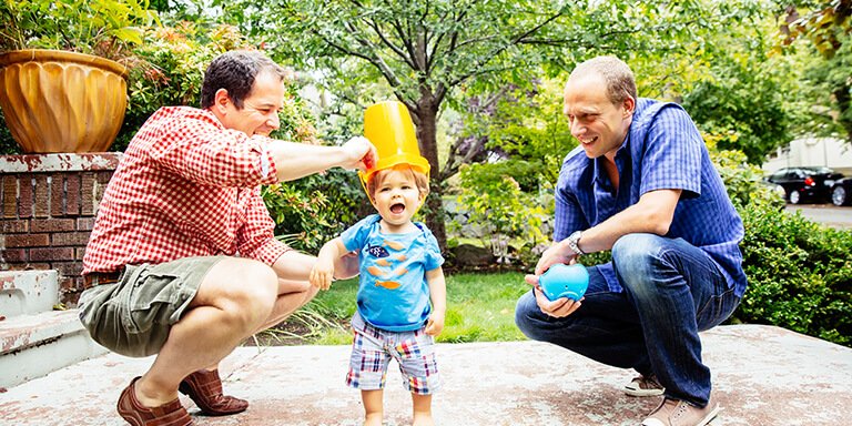 A father and son playing with buckets in the backyard with their grandfather 