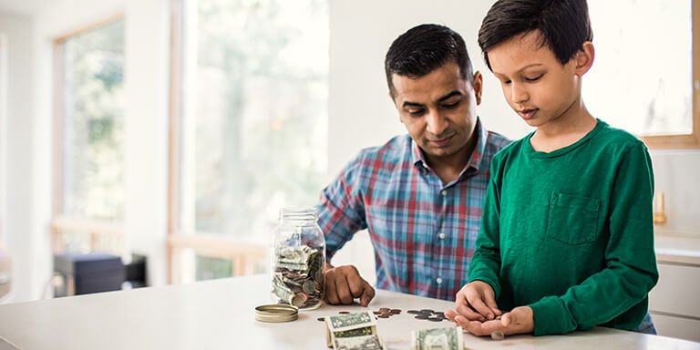 A young boy learning to count money at the kitchen table with his dad 