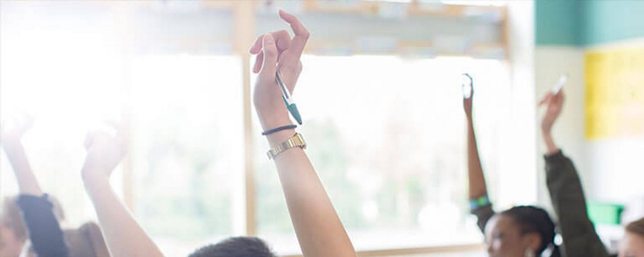 Students raising their hands to answer a question in a classroom