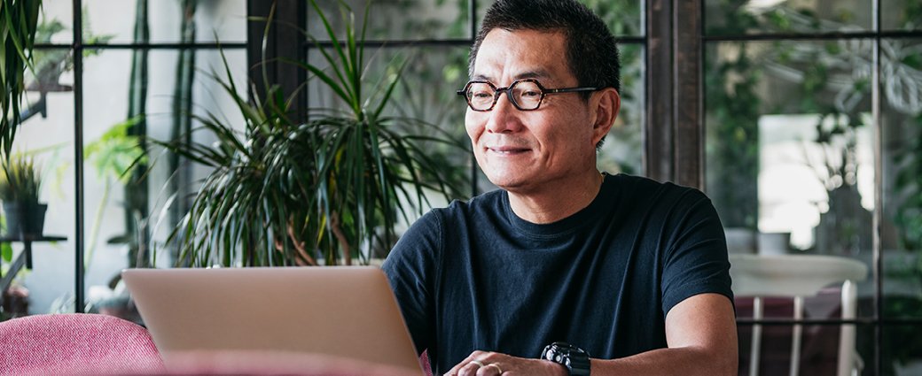 A cheerful young adult male is captured in a portrait, engaging with a tablet computer among people.