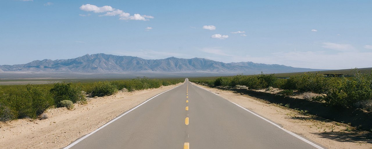 Wide open highway road with mountain ranges in the background