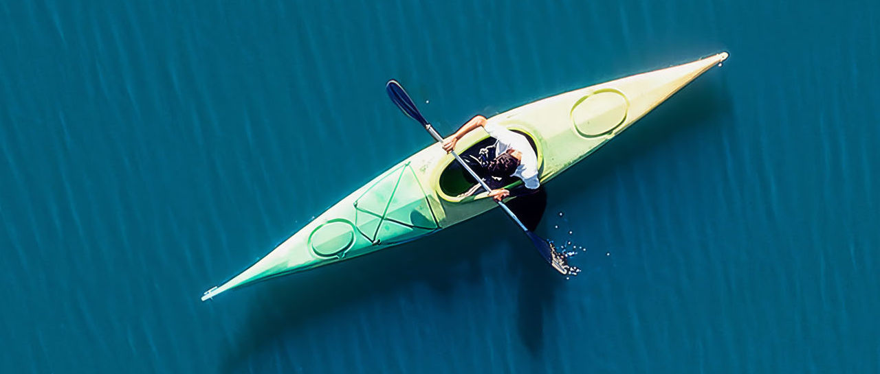 Aerial view of a person kayaking on calm blue water.