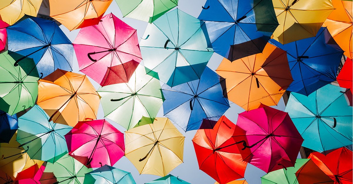 An overhead image of several opened umbrellas in a variety of bright colours.