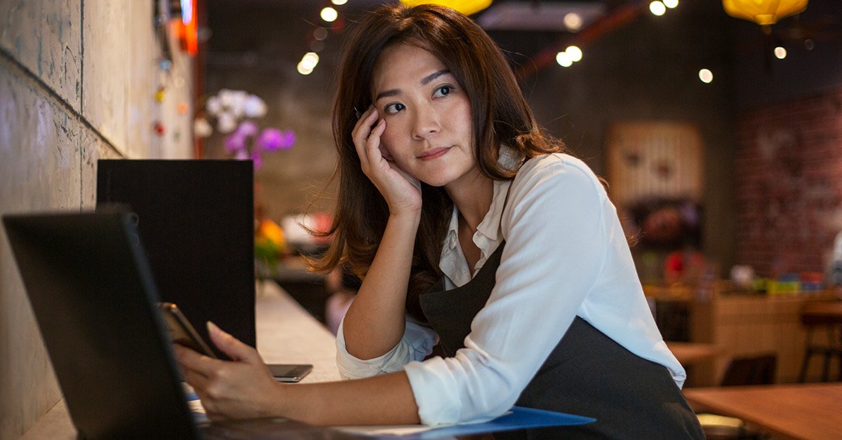 A young adult woman is conducting business activities in a café, showcasing female entrepreneurship.