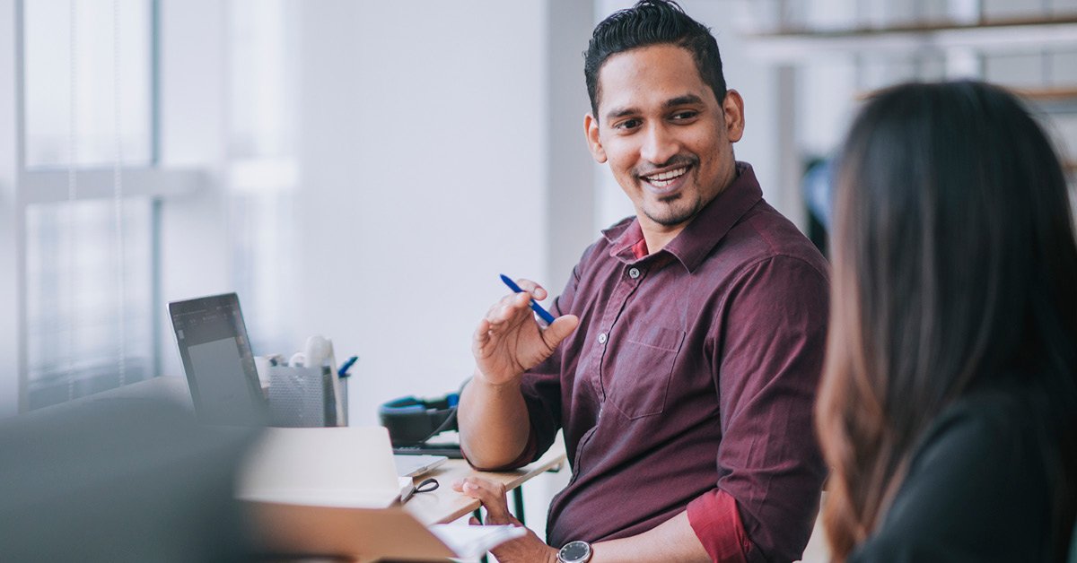 An adult businesswoman is diligently working at her desk in an office setting, using her computer.