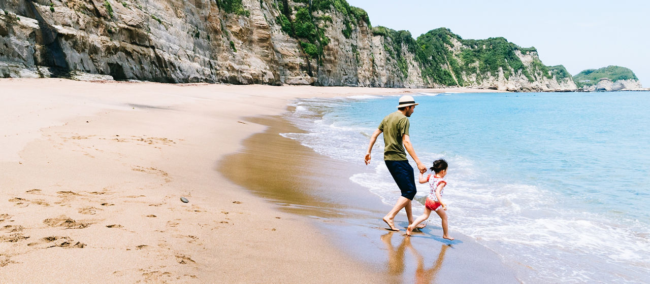 Father and his little girl having fun on a deserted beach with cliff, Chiba, Japan