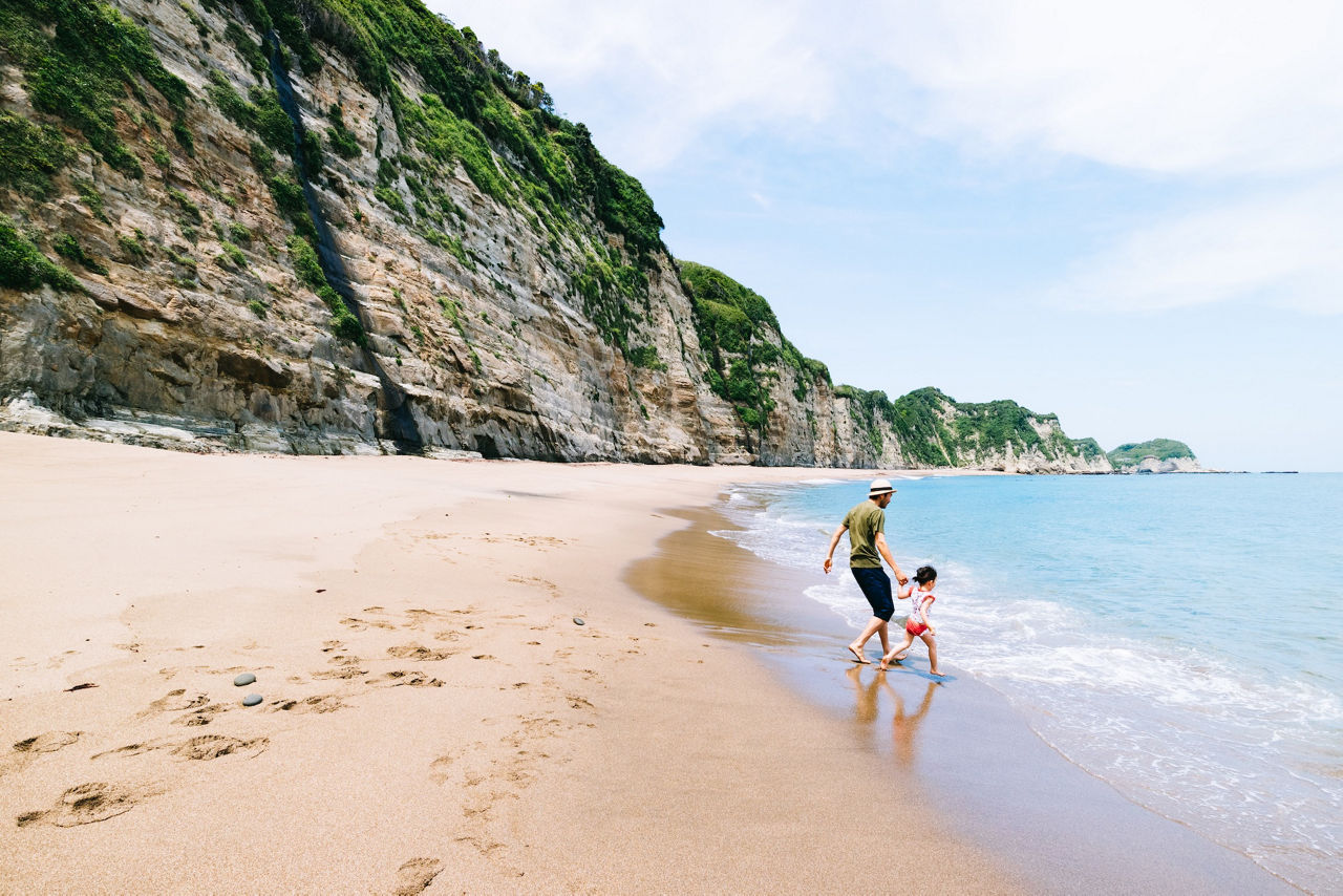 Father and his little girl having fun on a deserted beach with cliff, Chiba, Japan