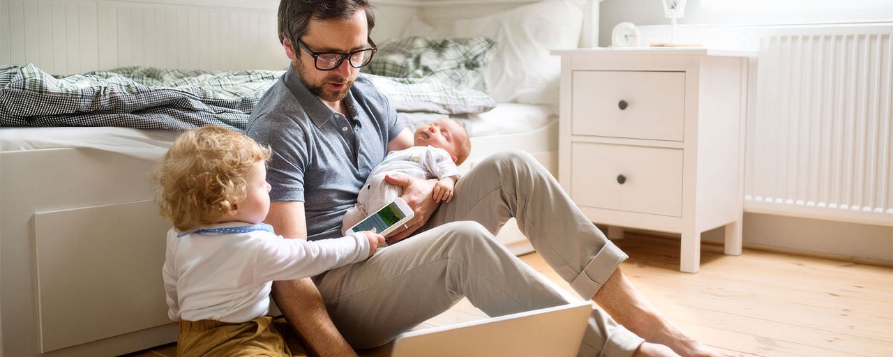 Father with his little son and baby daughter working on his computer from home