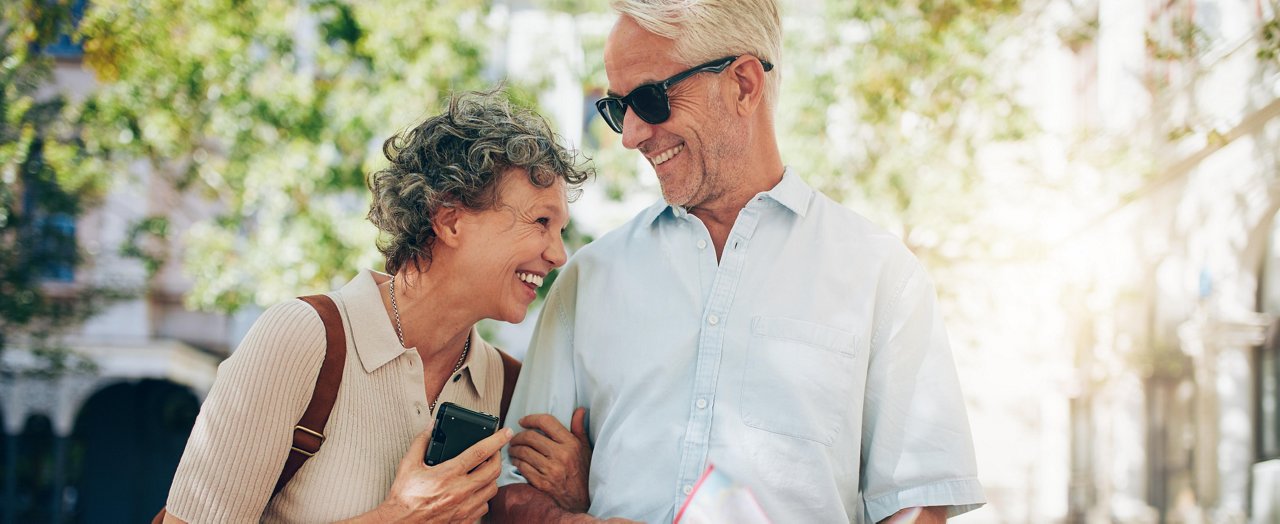 Couple de personnes âgées souriantes marchant dans une rue de la ville 