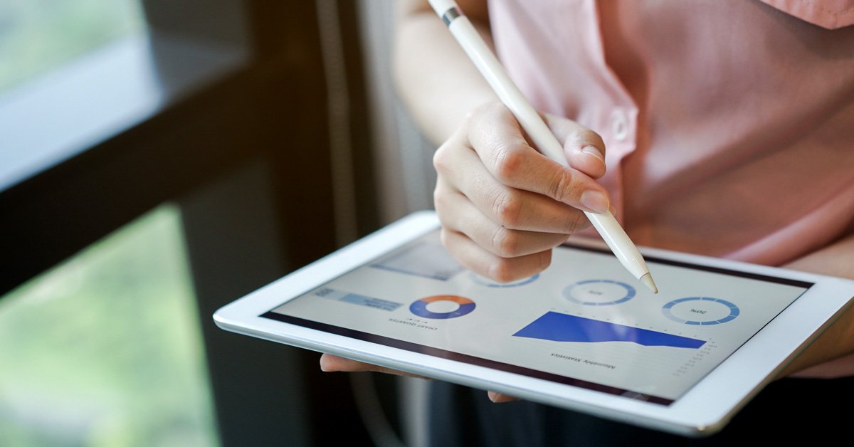 Un homme d'affaires dans un environnement de bureau utilise des technologies modernes, examinant des documents commerciaux avec une tablette et un stylo.