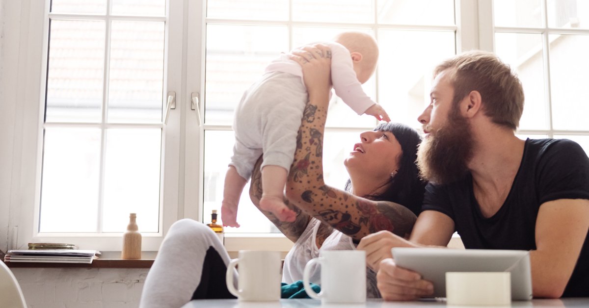 Un jeune couple joyeux prépare un repas ensemble dans leur cuisine domestique, incarnant le bonheur familial.