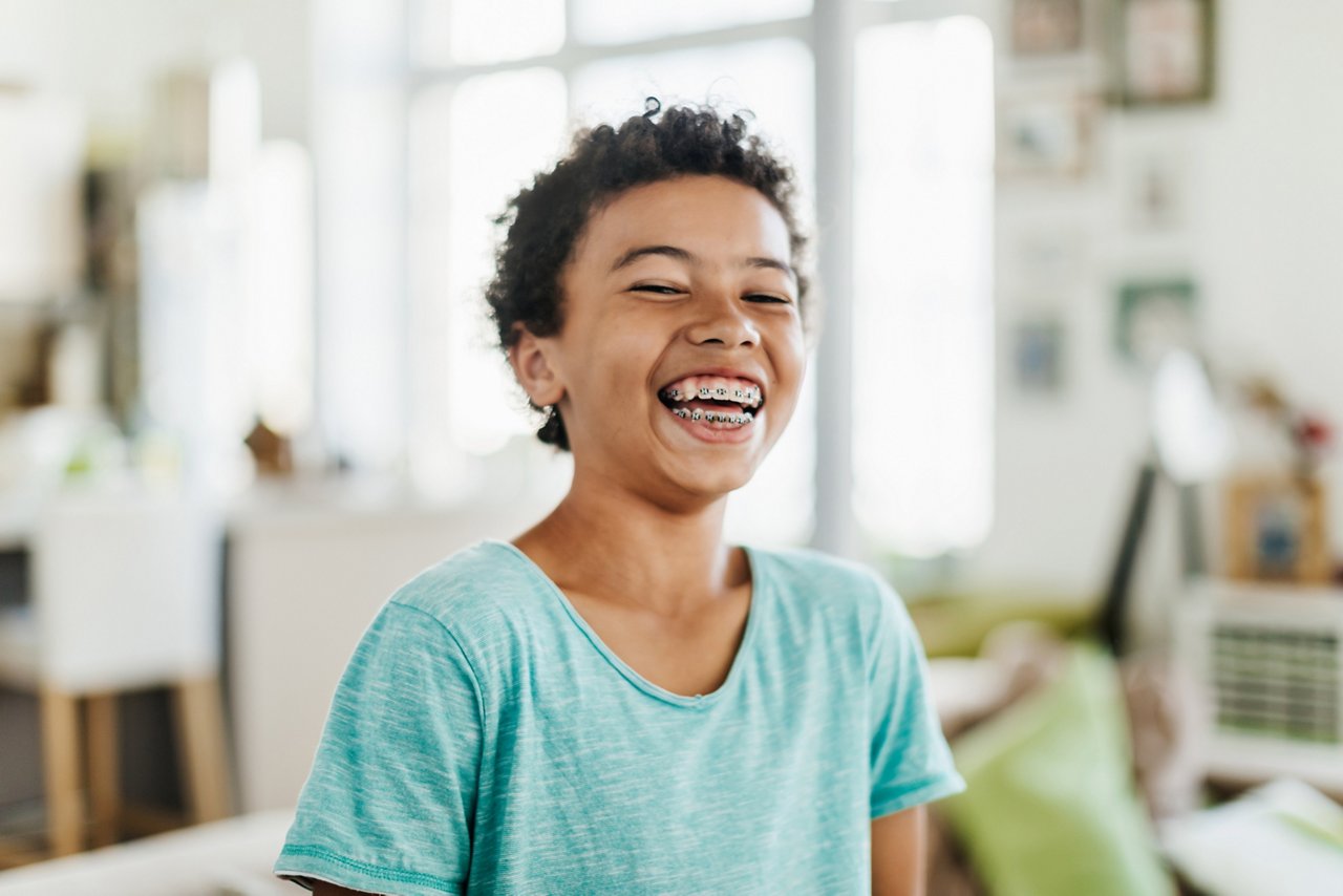 A portrait of a young boy with brace smiling at home.