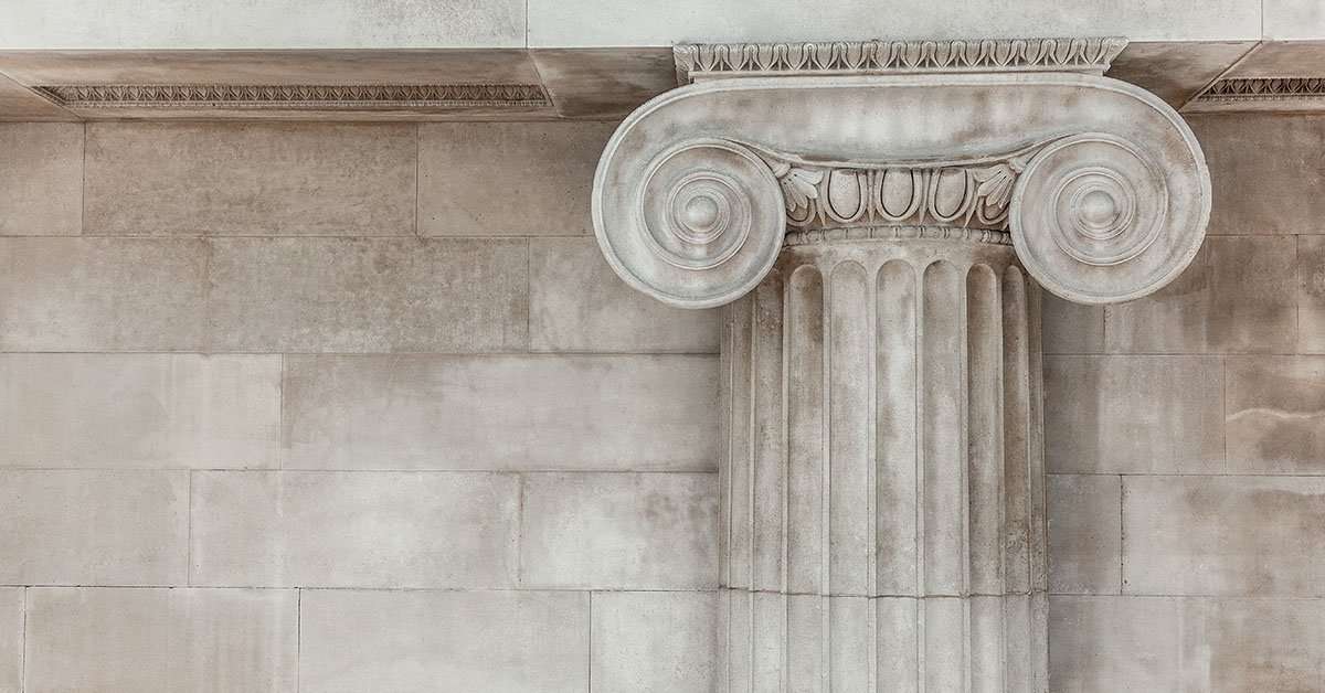 The ancient art and architecture of the old capital building, with its detailed stone columns, form a striking background.