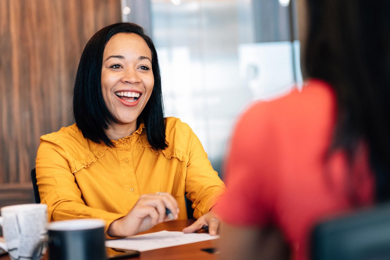 A young businesswoman is captured in a professional portrait, sitting in a cafe while attending to her work.