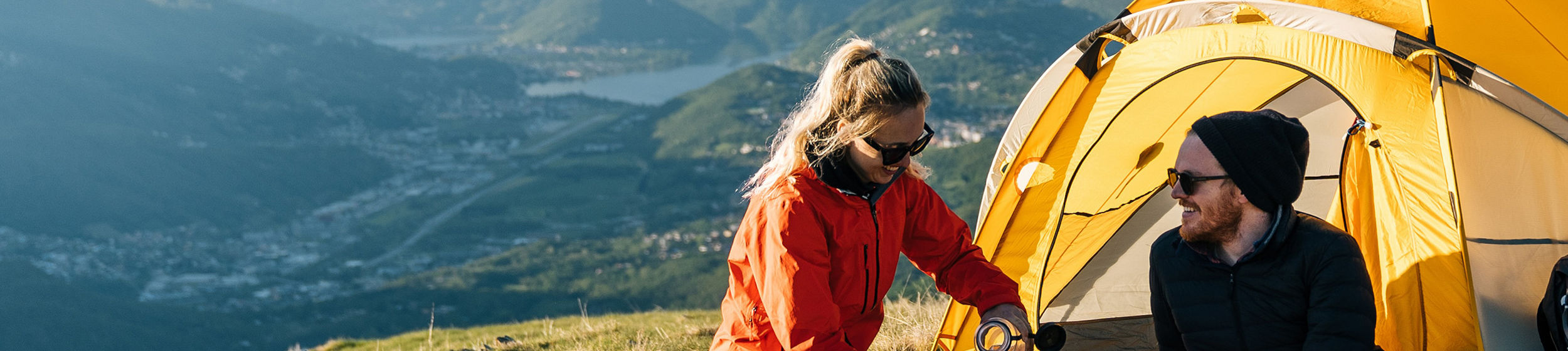 Couple camping with yellow tent on mountain ridge
