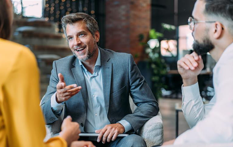 Trois personnes assises dans un bureau modern, en pleine discussion.