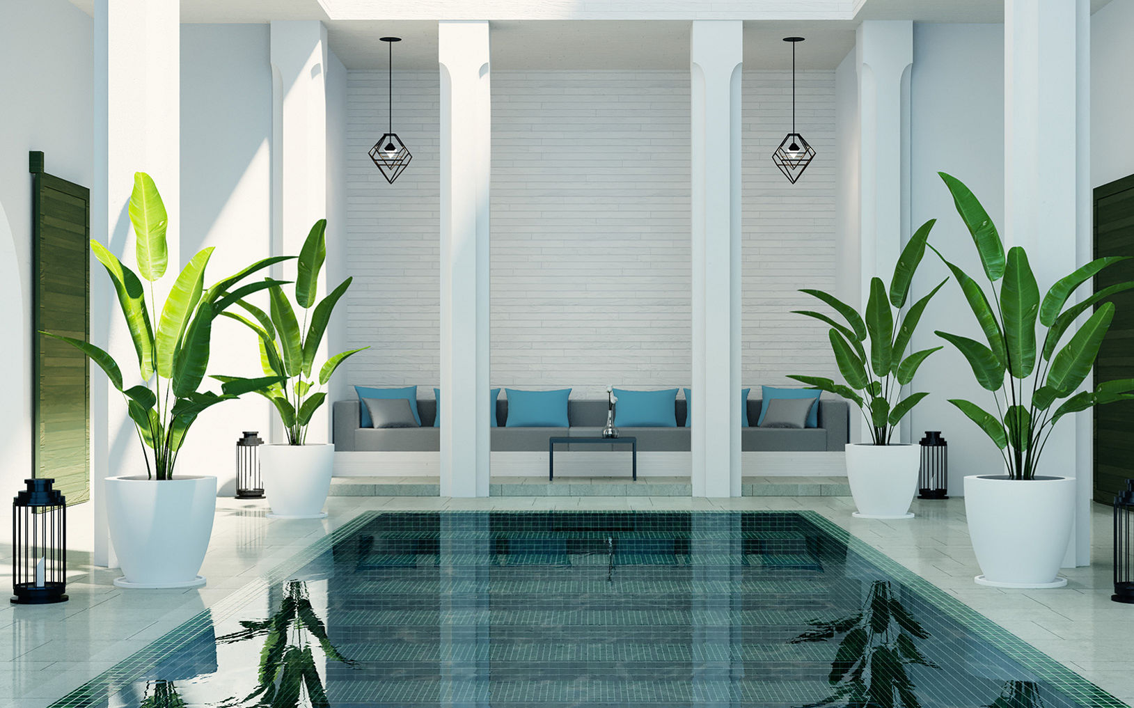 A serene indoor pool is framed by tall white columns and glossy tiled flooring. Large potted tropical plants line both sides of the water, adding lush greenery to the minimalist space. In the background, a seating area with cushions sits against a white wall beneath two hanging pendant lights. Black lanterns on the floor contribute to the calm, spa-like atmosphere.