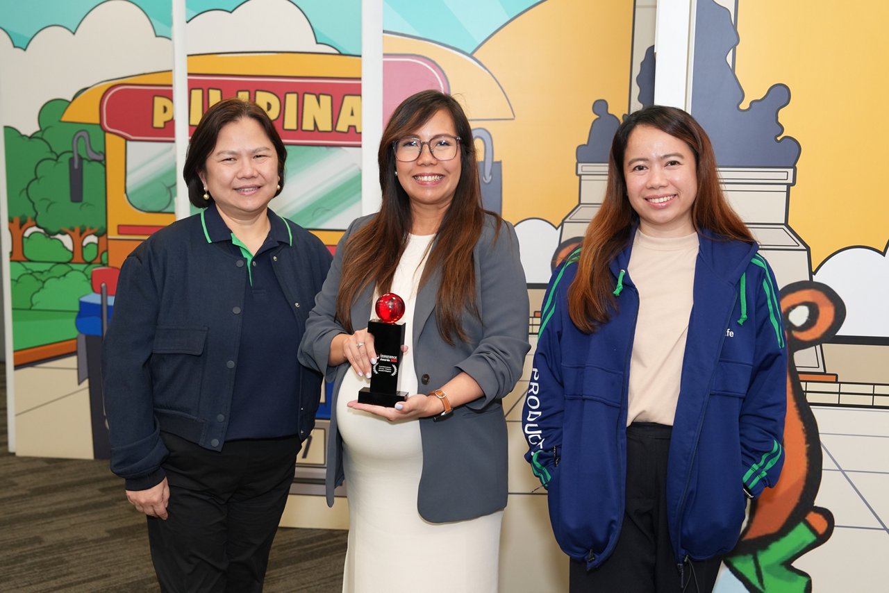 Three women posing with red award trophy