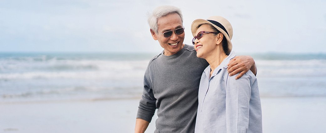 A joyful couple, both adults, express their love and happiness on a serene beach setting.