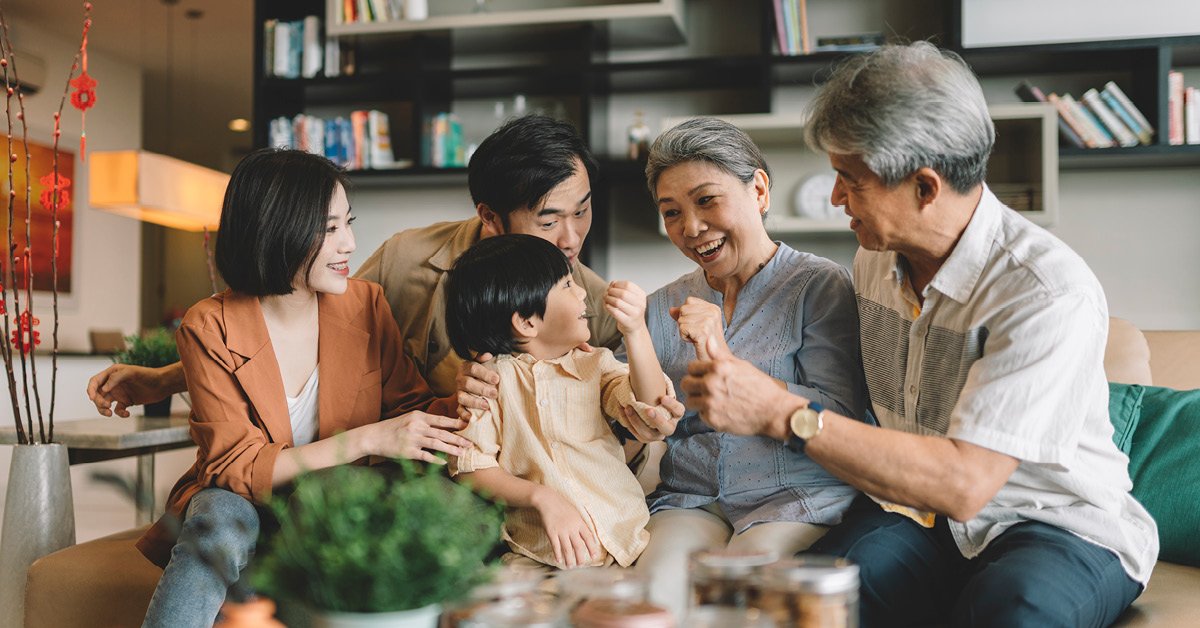 Multi-generational family, sitting on couch together and laughing.