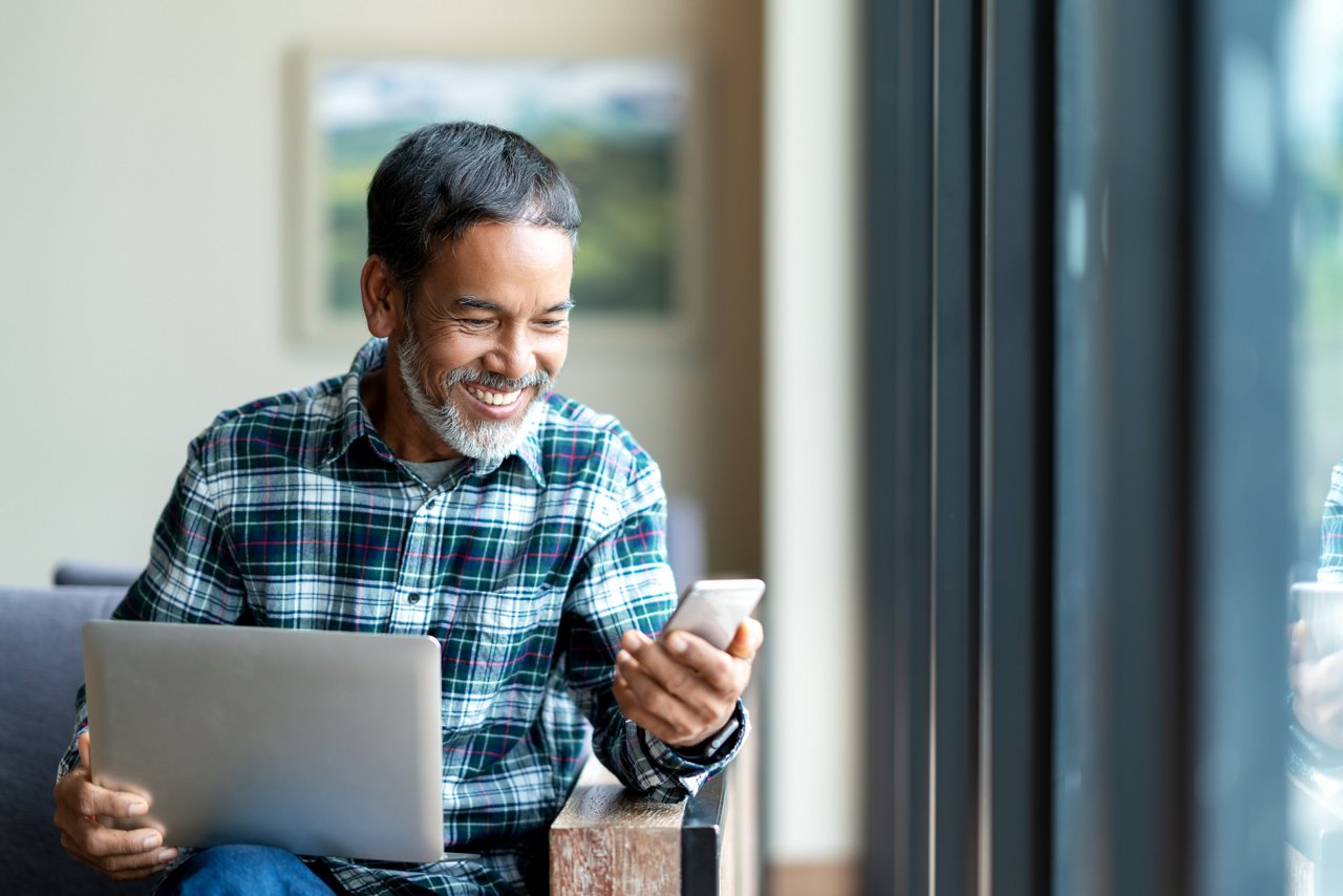 Man sitting at a desk texting on a cell phone