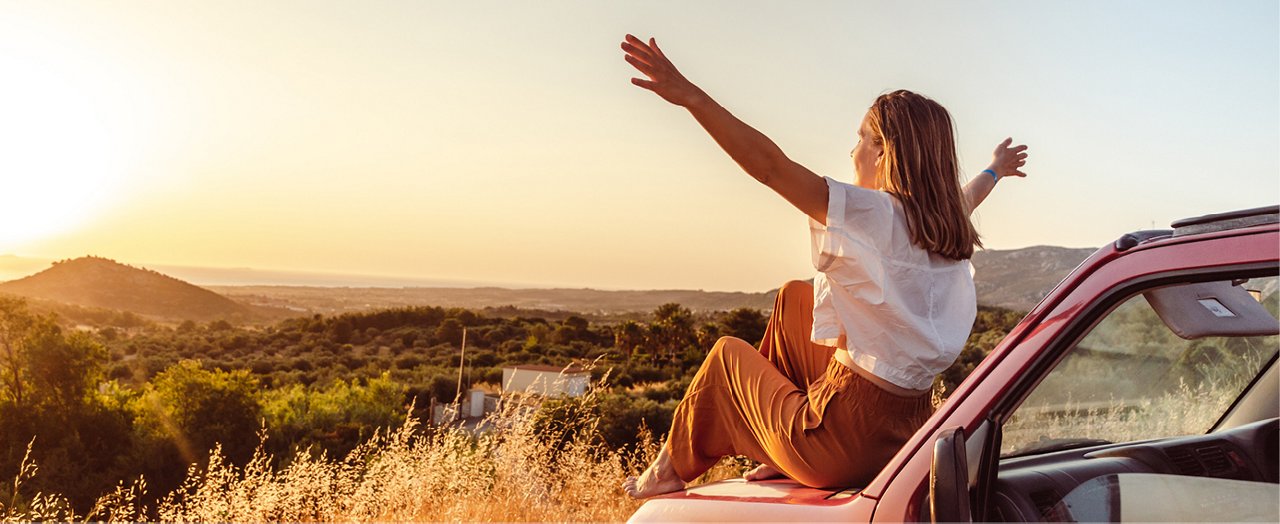 Une jeune femme ravie admire un magnifique coucher de soleil estival, incarnant la vitalité de la vie.