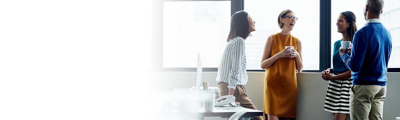 Une jeune femme et un homme adulte travaillent assidûment sur leurs ordinateurs dans leur bureau à l'intérieur.