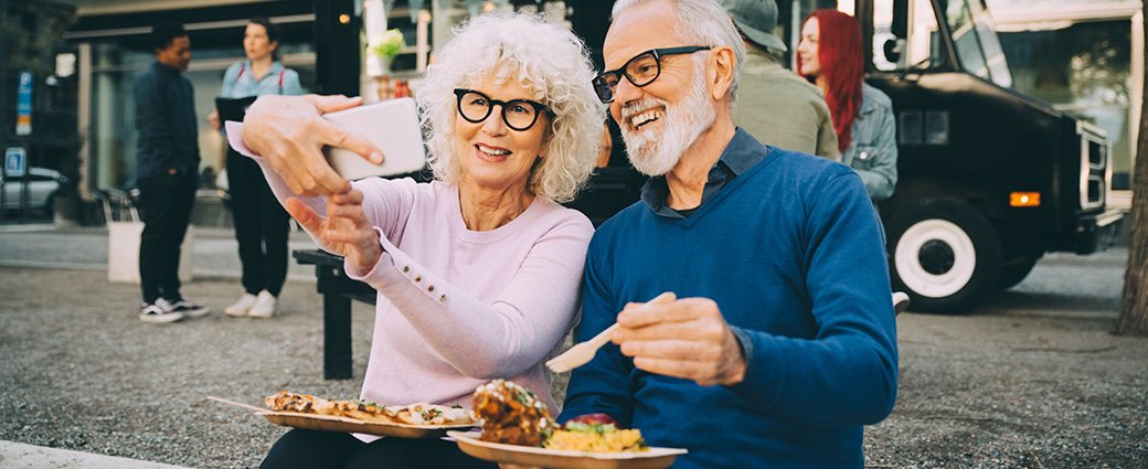 Retirement aged couple looking at a phone screen on a busy city street