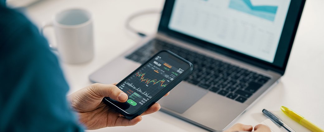 Une main professionnelle manipule la technologie, naviguant habilement sur un clavier d'ordinateur portable, un ordinateur et un téléphone mobile pour la communication d'entreprise.