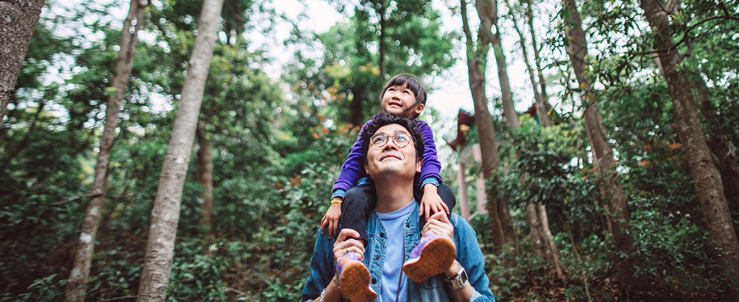 man standing in the forest with a small child on his shoulders