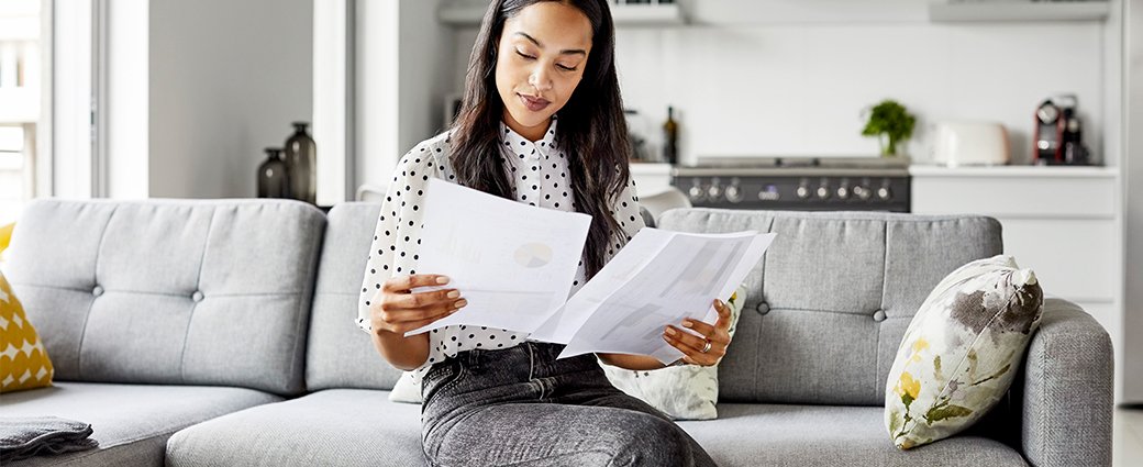 woman sitting on sofa looking at financial documents