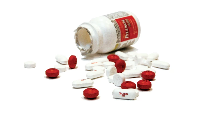 A bottle of Tylenol (acetaminophen) with pills spilled out.