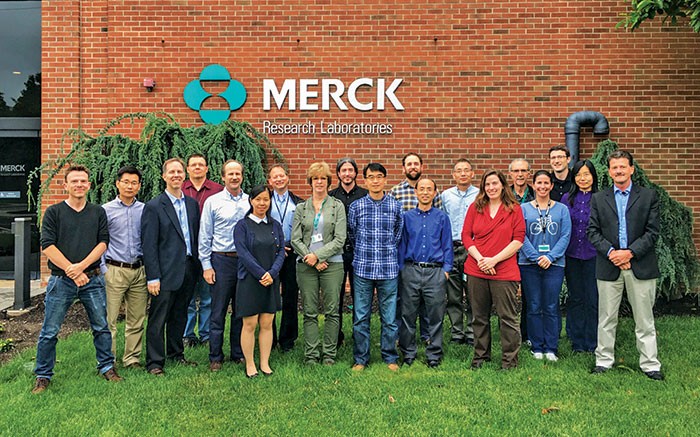 A photo shows the Merck research team standing in front of Merck Research Laboratories building.