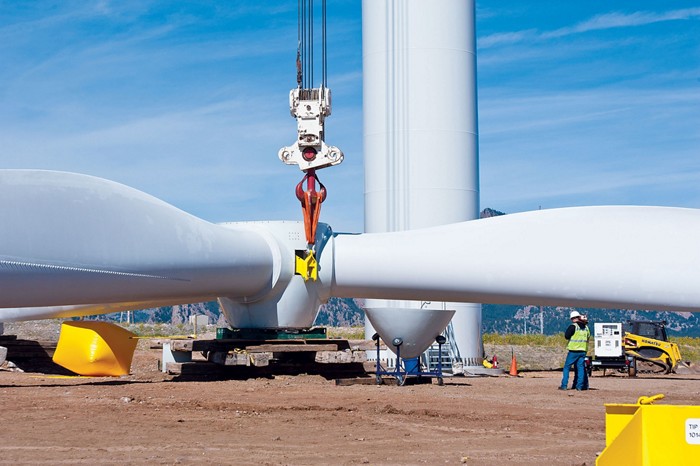 This image shows people and machinery moving a large wind turbine blade.
