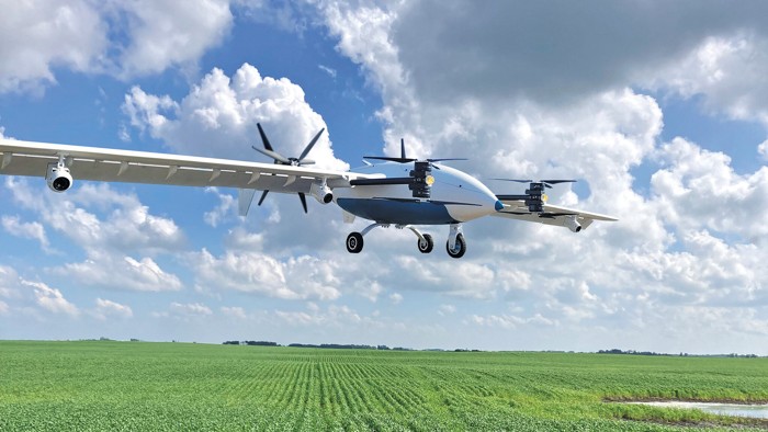 Um drone de asa fixa sobrevoa um campo agrícola.