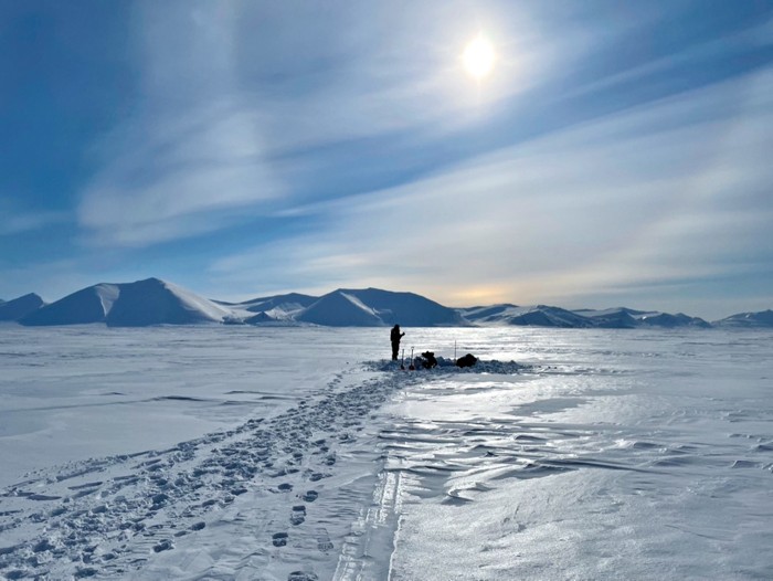 The silhouette of a person on a beautiful, white Arctic landscape.