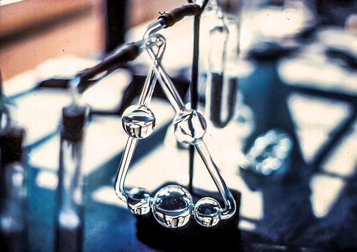 A piece of chemistry glassware made from a triangular glass tube that balloons out to form in-line bubbles. The bottom side has three bulbs, and each of the two upward sides has one bulb.