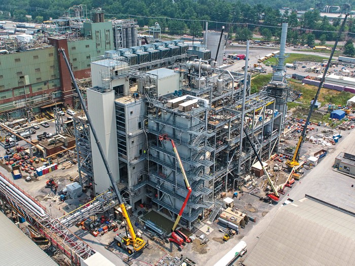 A chemical plant under construction with scaffolding and cranes.
