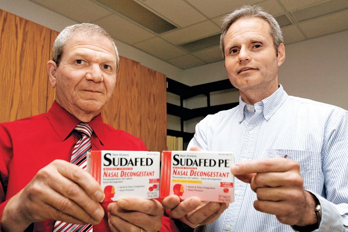 Two men hold up packages of Sudafed and Sudafed PE.