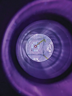 Inside a long metal tube with an array of light-emitting diode lights glowing blue purple at the far end.