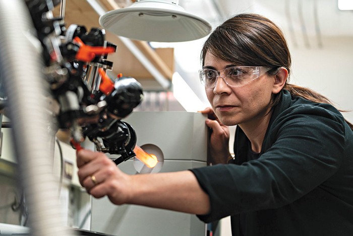 Woman wearing safety goggles looking at instrumentation in a laboratory.