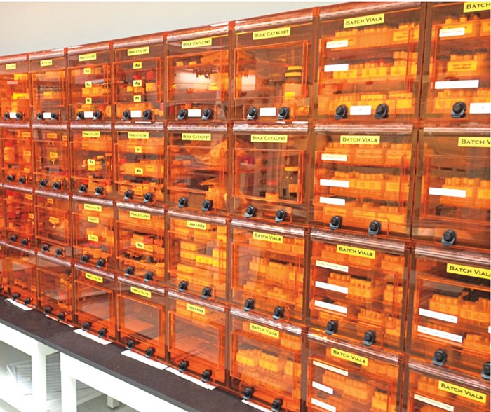 A long row of translucent, orange storage containers with yellow labels, each containing three shelves of vials.