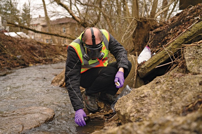 Andrew Whelton collecting a water sample in a creek in East Palestine.