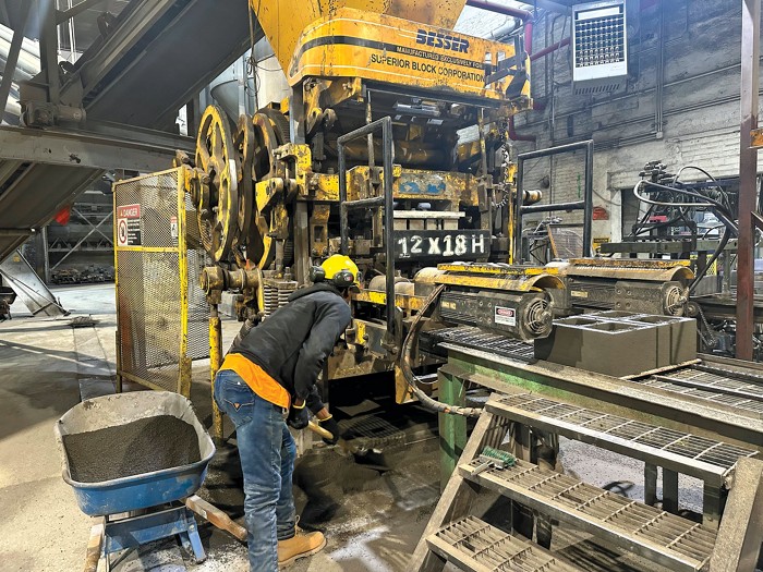 A yellow machine the size of a semitruck cab operates inside a factory.
