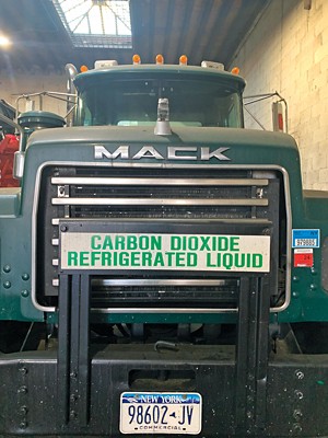 The grill of a Mack deisel truck carries a placard that reads "CARBON DIOXIDE REFRIGERATED LIQUID."