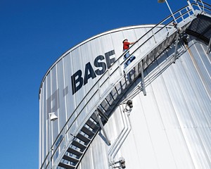 A person climbs curved stairs on the outside of a chemical tank.