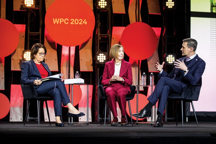 Three executives sit on a stage at the World Petrochemical Forum. 